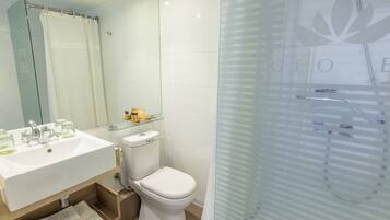 A modern bathroom with a glass shower enclosure, a white sink with a mirror above it, and a toilet.