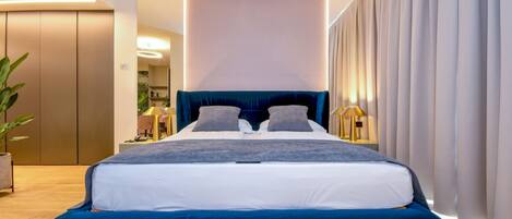 A modern bedroom with a large bed, a bedside table, and a nightstand.
