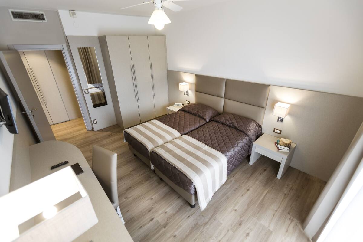 A modern bedroom with a bed, bedside tables, and a wardrobe.