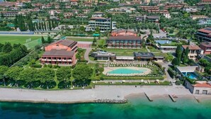 An aerial view of a hotel complex with multiple buildings, a swimming pool, and a beach area. - Hotel Du Lac (Limone sul Garda)