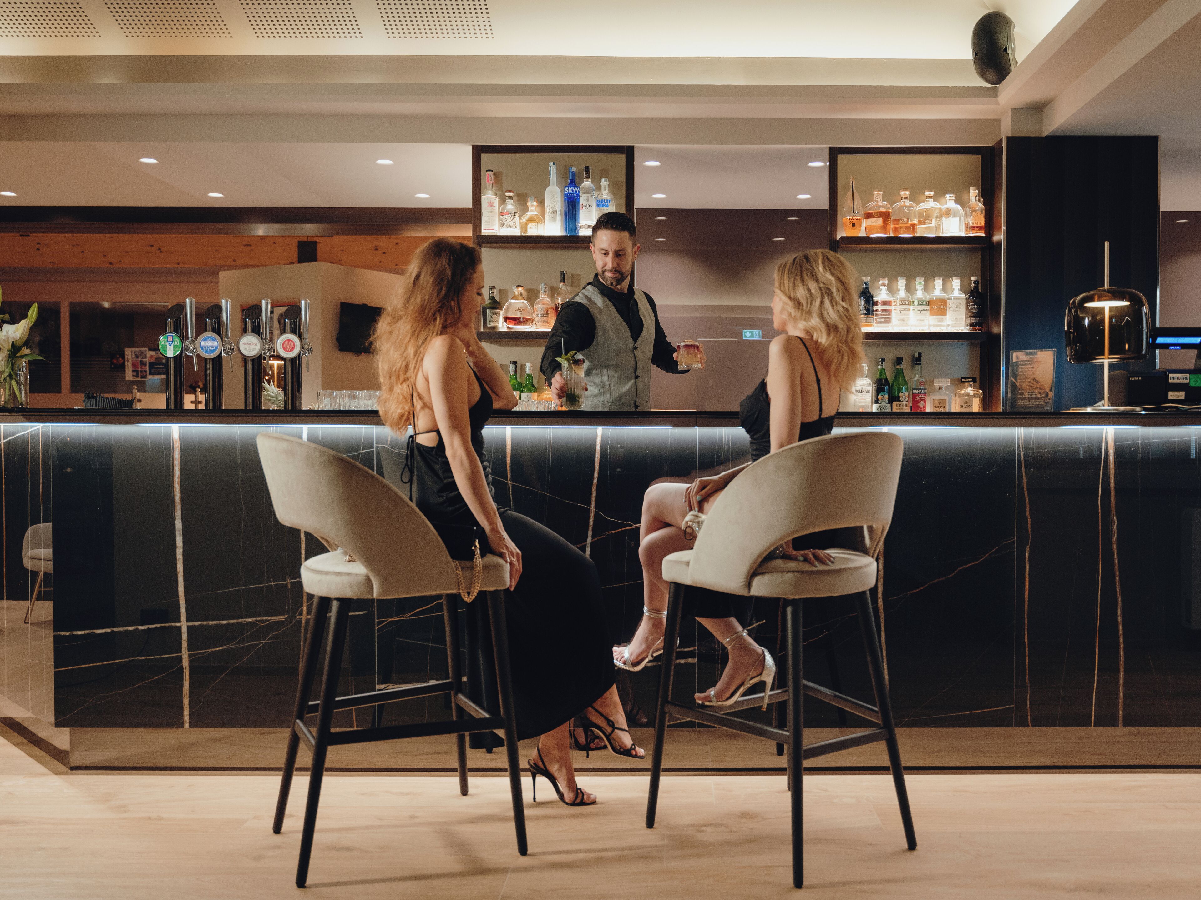 A bar area with a counter, stools, and a bartender.