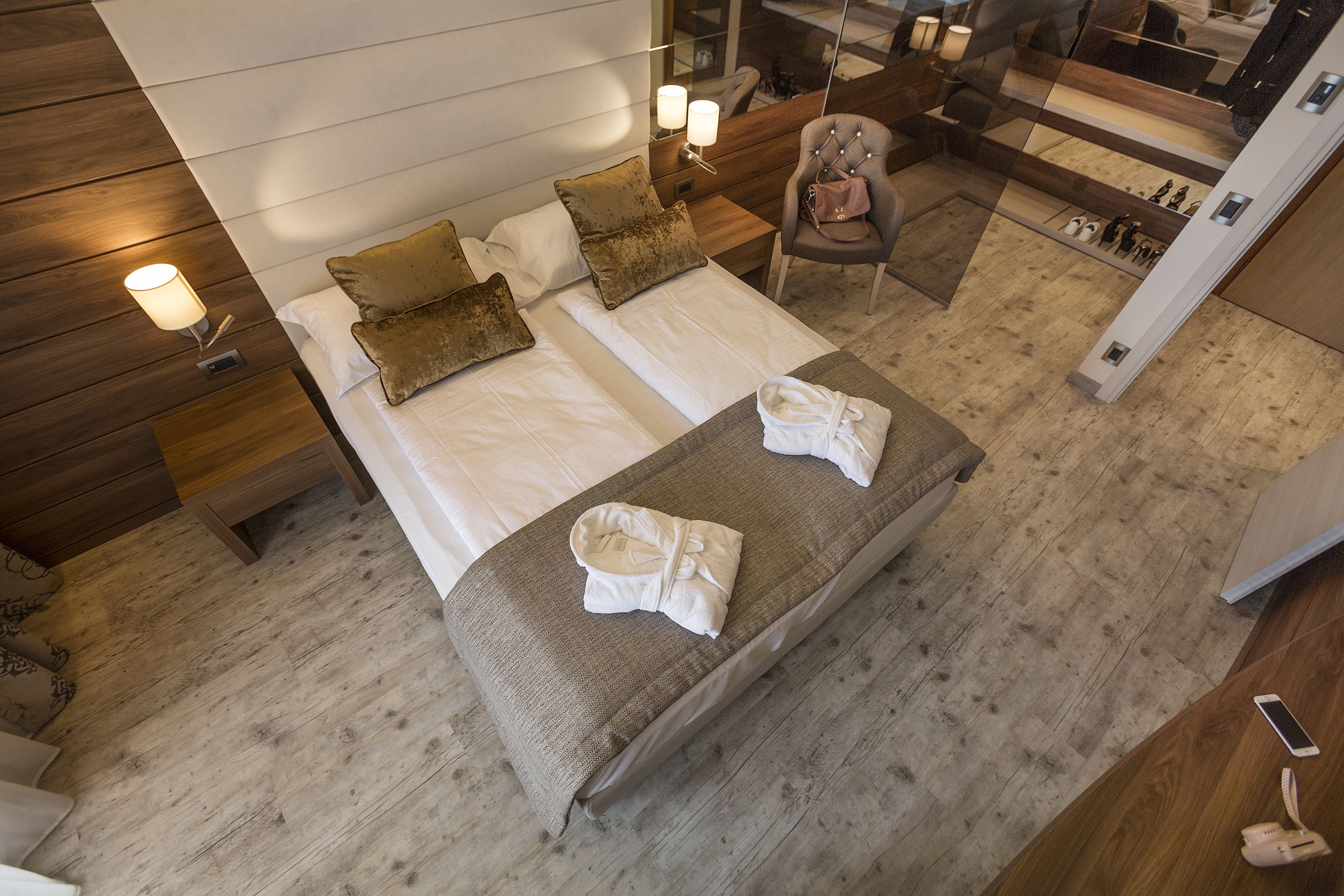 A hotel room with a large bed, two bedside tables, a chair, and a mirror.