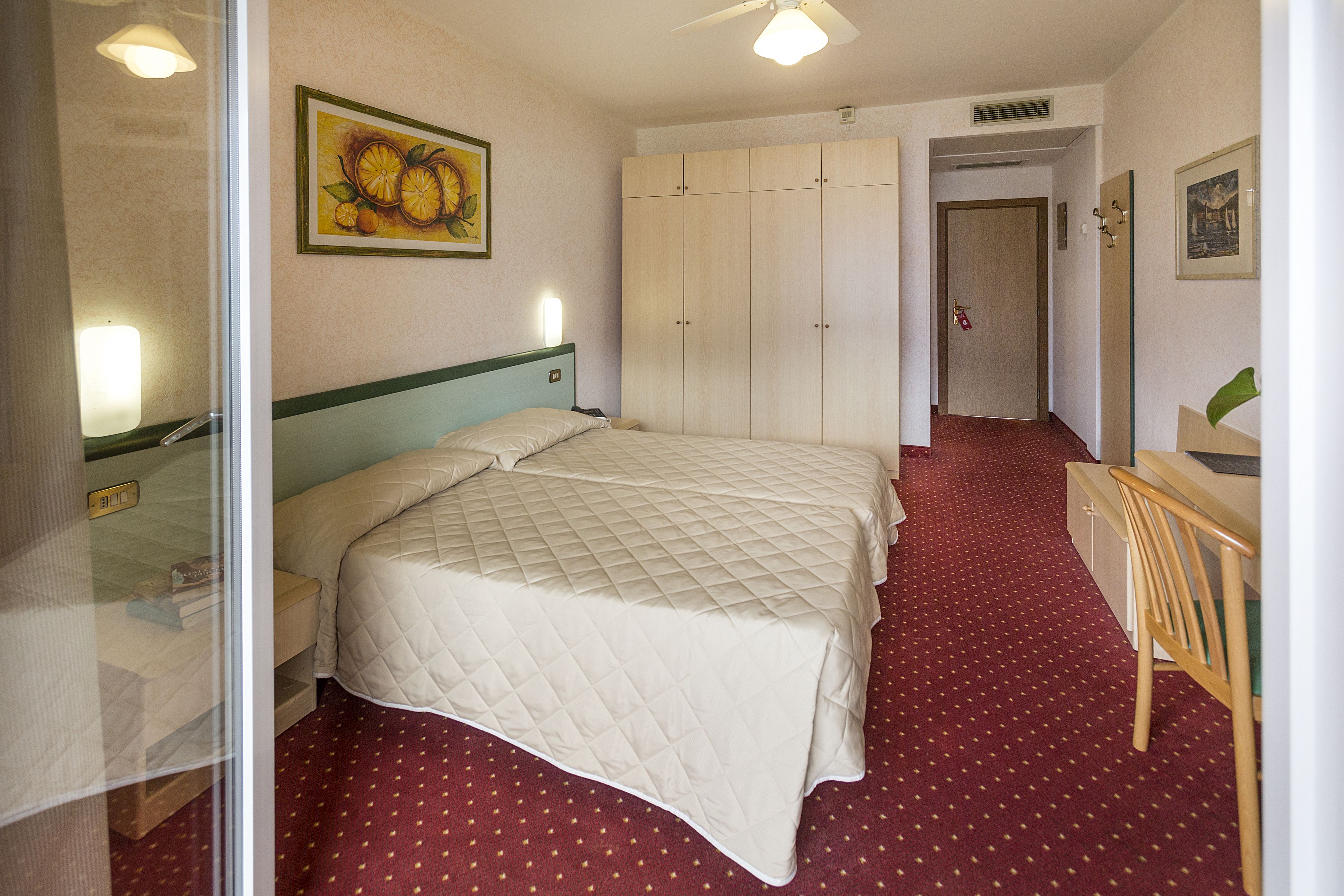 Una habitación de hotel con cama, escritorio, silla y armario.