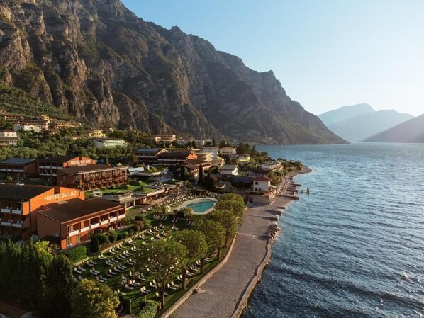 A coastal hotel with multiple buildings, a swimming pool, and a beach.
