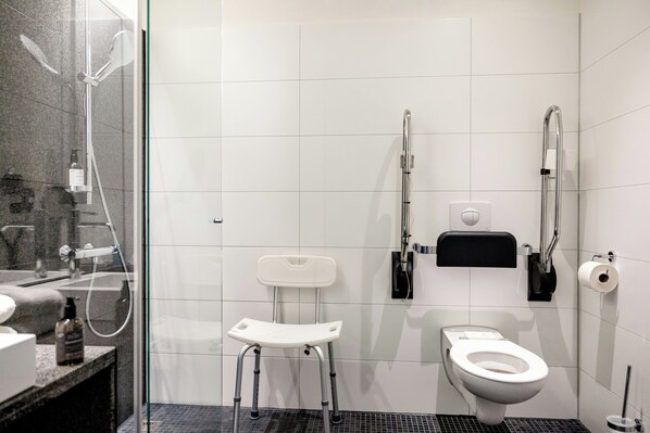 Un baño moderno con ducha, inodoro y un banco accesible para sillas de ruedas.