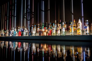 Un bar où l’on trouve une grande variété de bouteilles d’alcool et de verres.