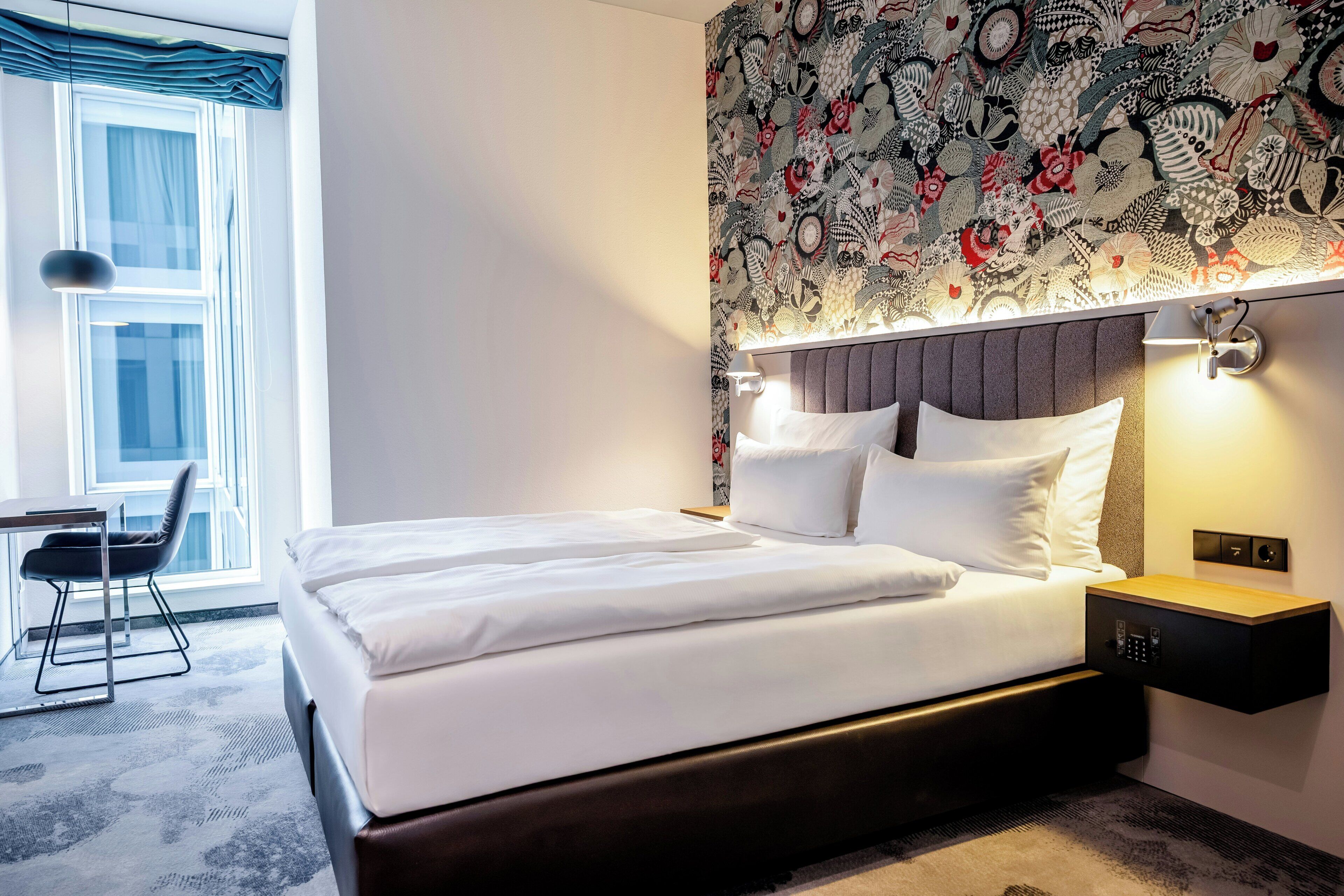 Una habitación de hotel moderna con una cama grande, un escritorio y una silla.