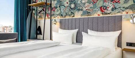 A hotel room with a large bed, a headboard with a patterned design, a bedside table, and a window with curtains.