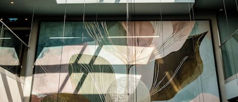 A modern interior with a skylight, abstract wall art, and hanging spherical light fixtures.