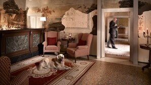 Een luxueuze kamer met een groot, versierd tapijt, een open haard en een hond die op de vloer rust.