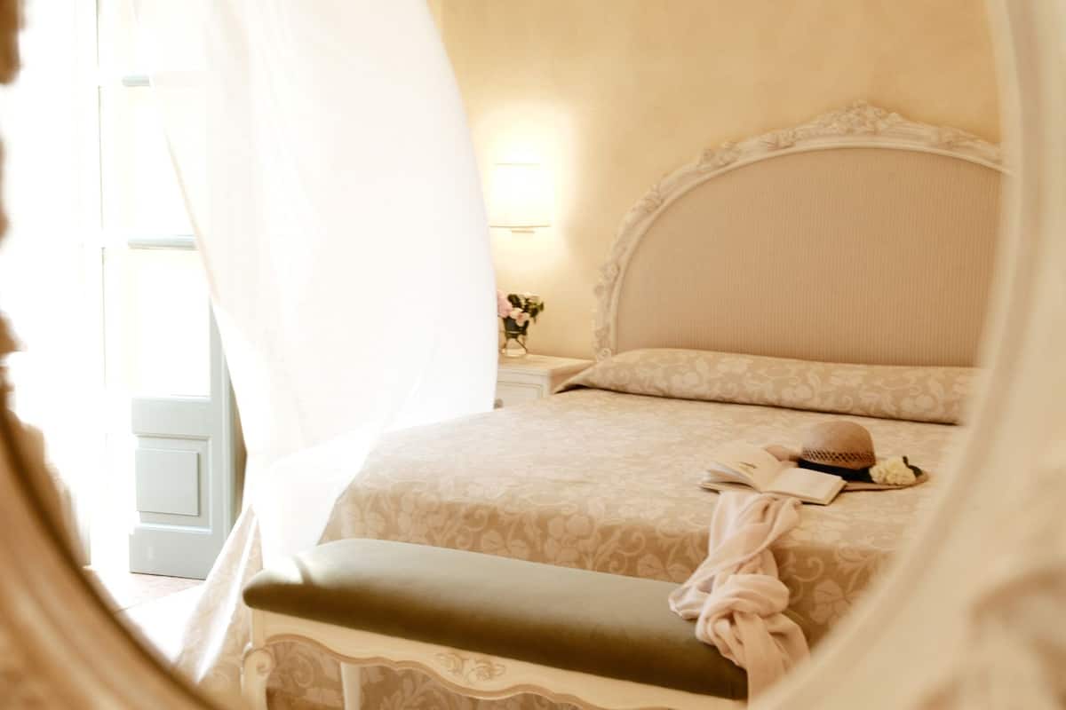 Une chambre à coucher avec un lit, une table de chevet, une lampe et une fenêtre avec des rideaux.