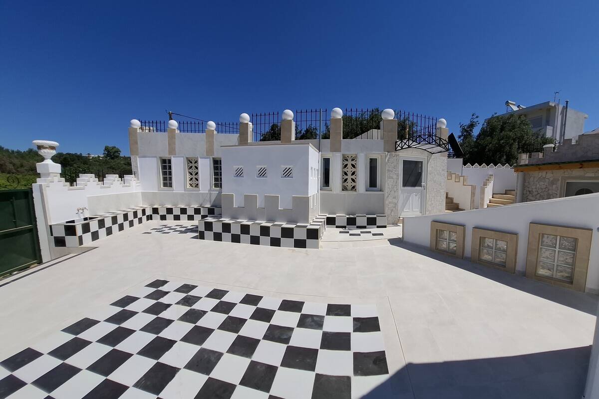 A modern building with a checkered floor, white walls, and a metal fence.
