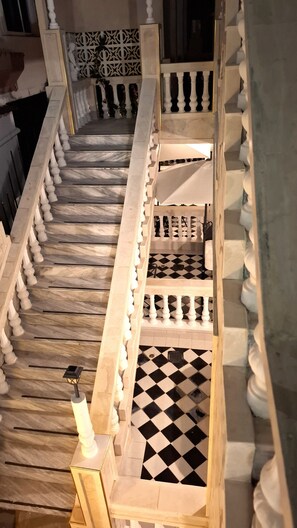 Eine Marmortreppe mit Balustraden, Schachbrettfußboden und einem dekorativen Wandmuster.