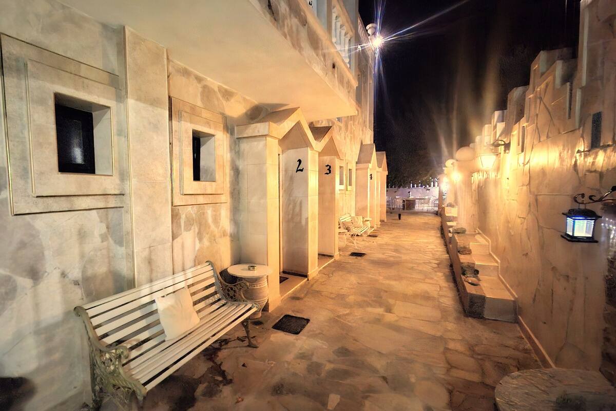 A narrow, stone-paved alleyway with benches and doors numbered 2 and 3.