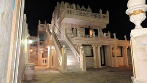 A grand, multi-level building with a prominent staircase, ornate railings, and classical architectural elements. - Castellino Studios (Rhodes)