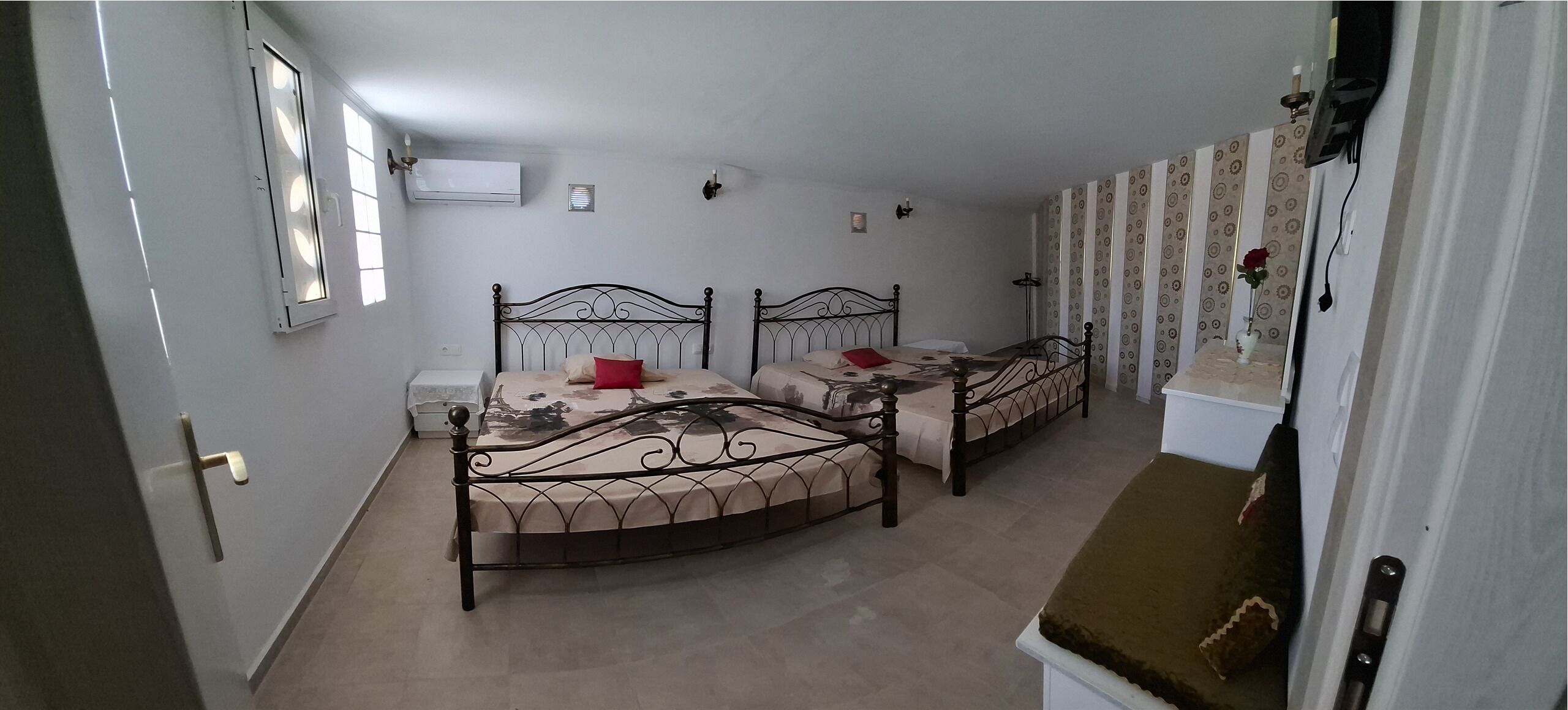 Quarto com duas camas, uma janela, ar condicionado e um espelho.