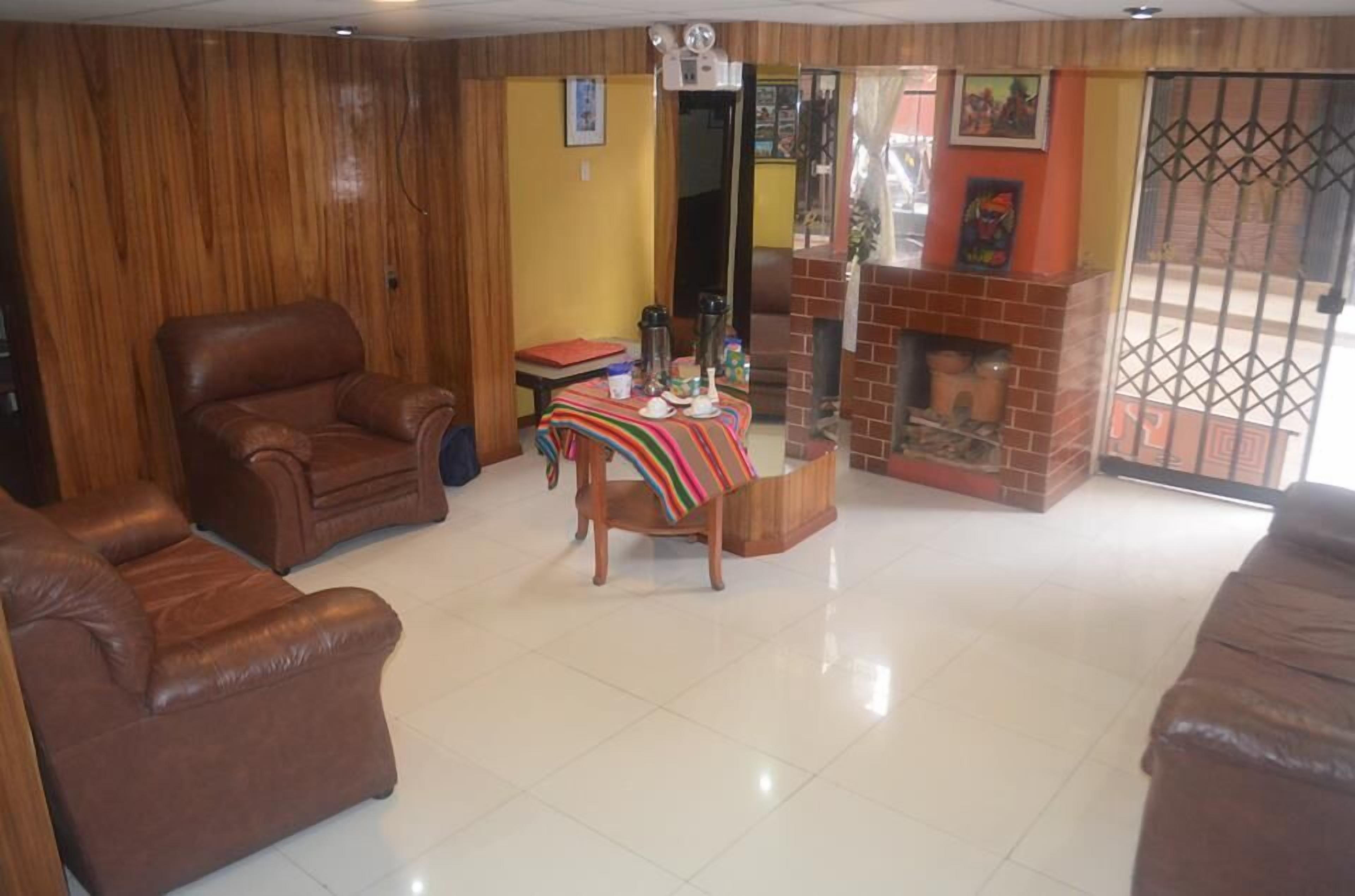 A living room with a brown leather sofa, a wooden coffee table with a striped tablecloth, and a brick fireplace.