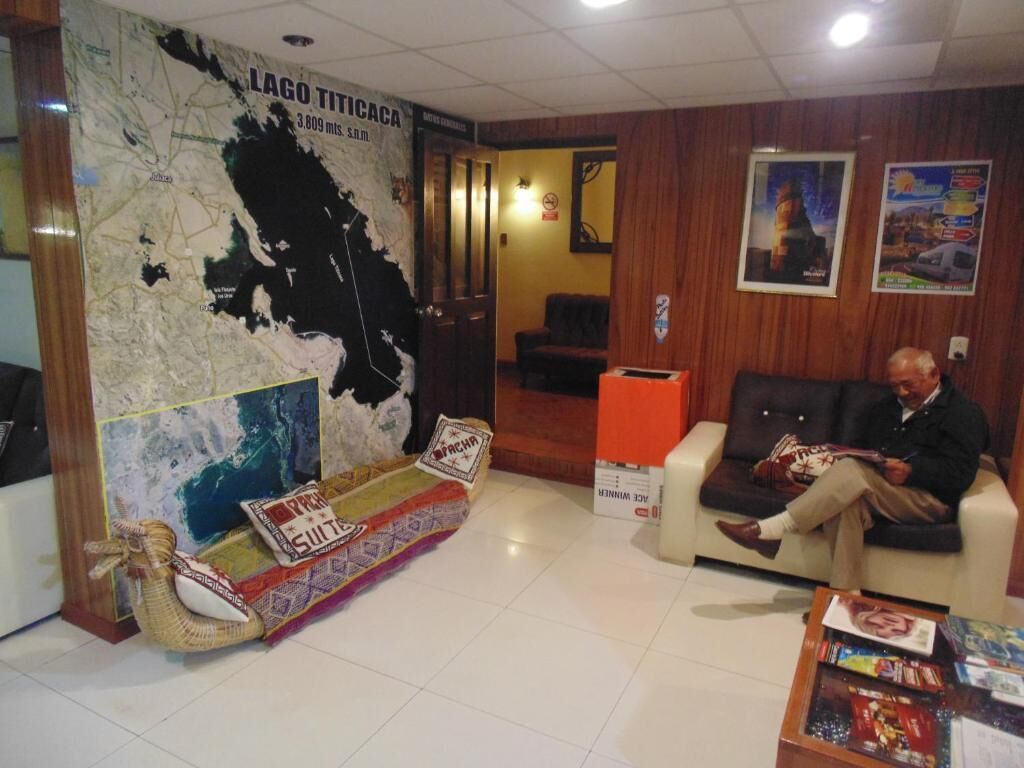 Un hall con un mapa, un sofá, una silla y una mesa con revistas.