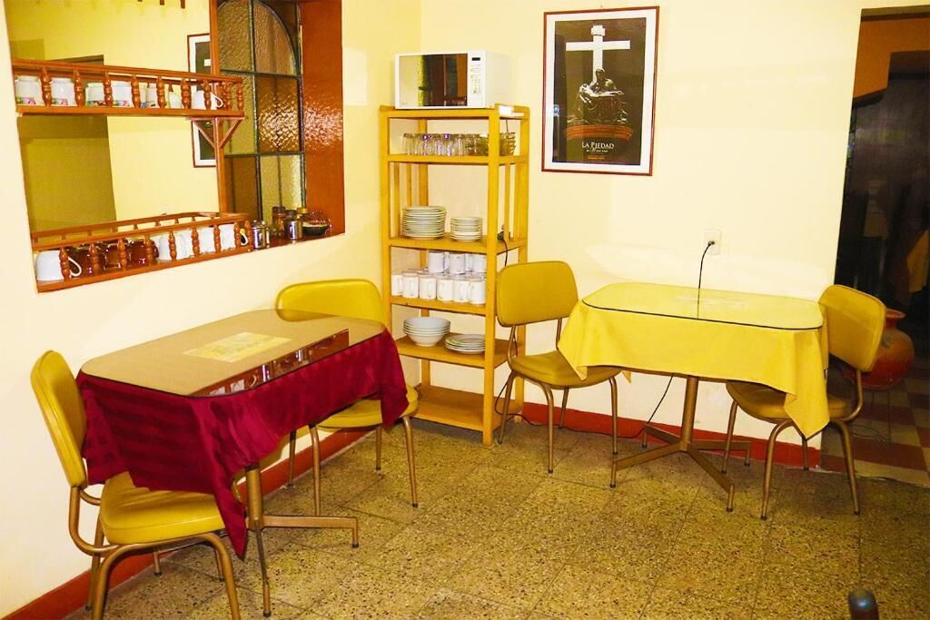 Un comedor con una mesa y sillas, un estante con vajilla y un cuadro en la pared.