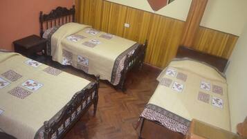 A room with two wooden beds, each with a patterned bedspread and a nightstand.
