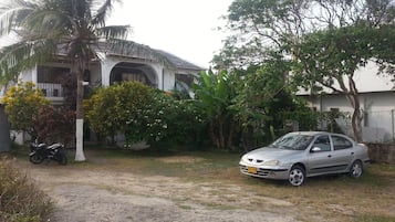 Un barrio residencial con una casa, un coche estacionado y una motocicleta.