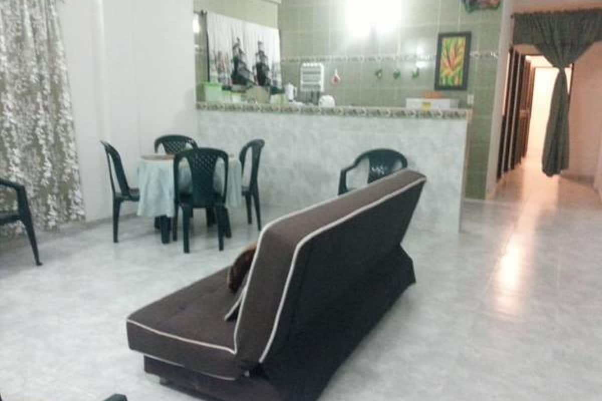 Una habitación con sofá, comedor con sillas y mesa, y cocina con mostrador y electrodomésticos.