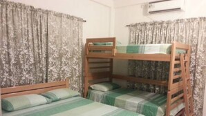 A room with bunk beds, floral curtains, and an air conditioning unit. - Ground Road Native Place (San Andrés)