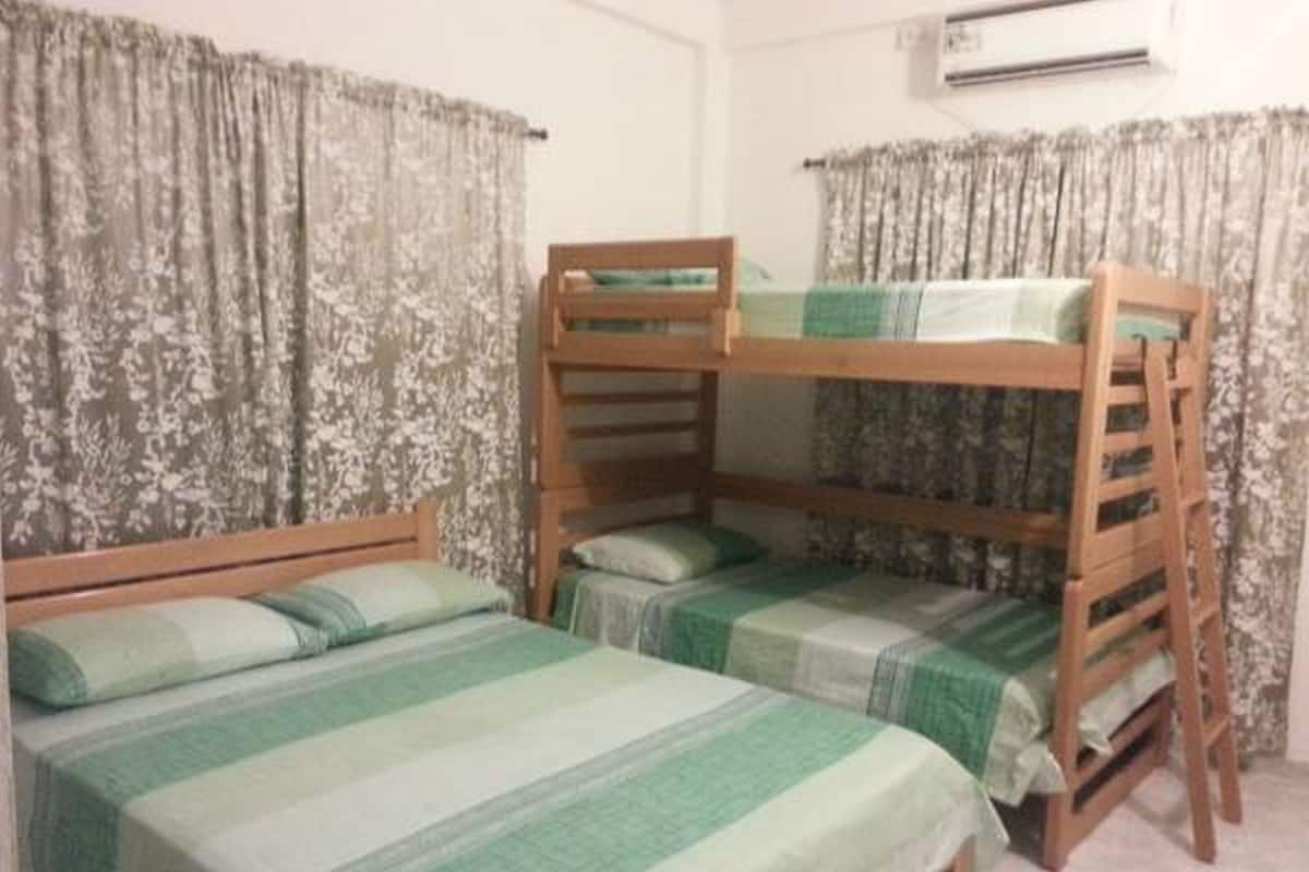 Una habitación con literas, cortinas con estampado floral y un equipo de aire acondicionado.