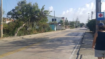 Una calle tranquila con un cartel médico, casas y árboles.