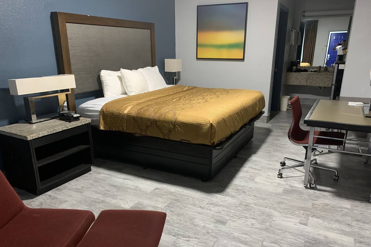 A hotel room with a bed, bedside tables, a desk, and a chair.