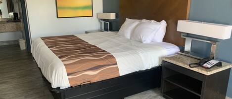 Een hotelkamer met een bed, nachtkastjes, een lamp, een telefoon en een schilderij aan de muur.