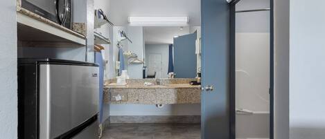 A compact kitchen with a refrigerator, microwave, and granite countertop.