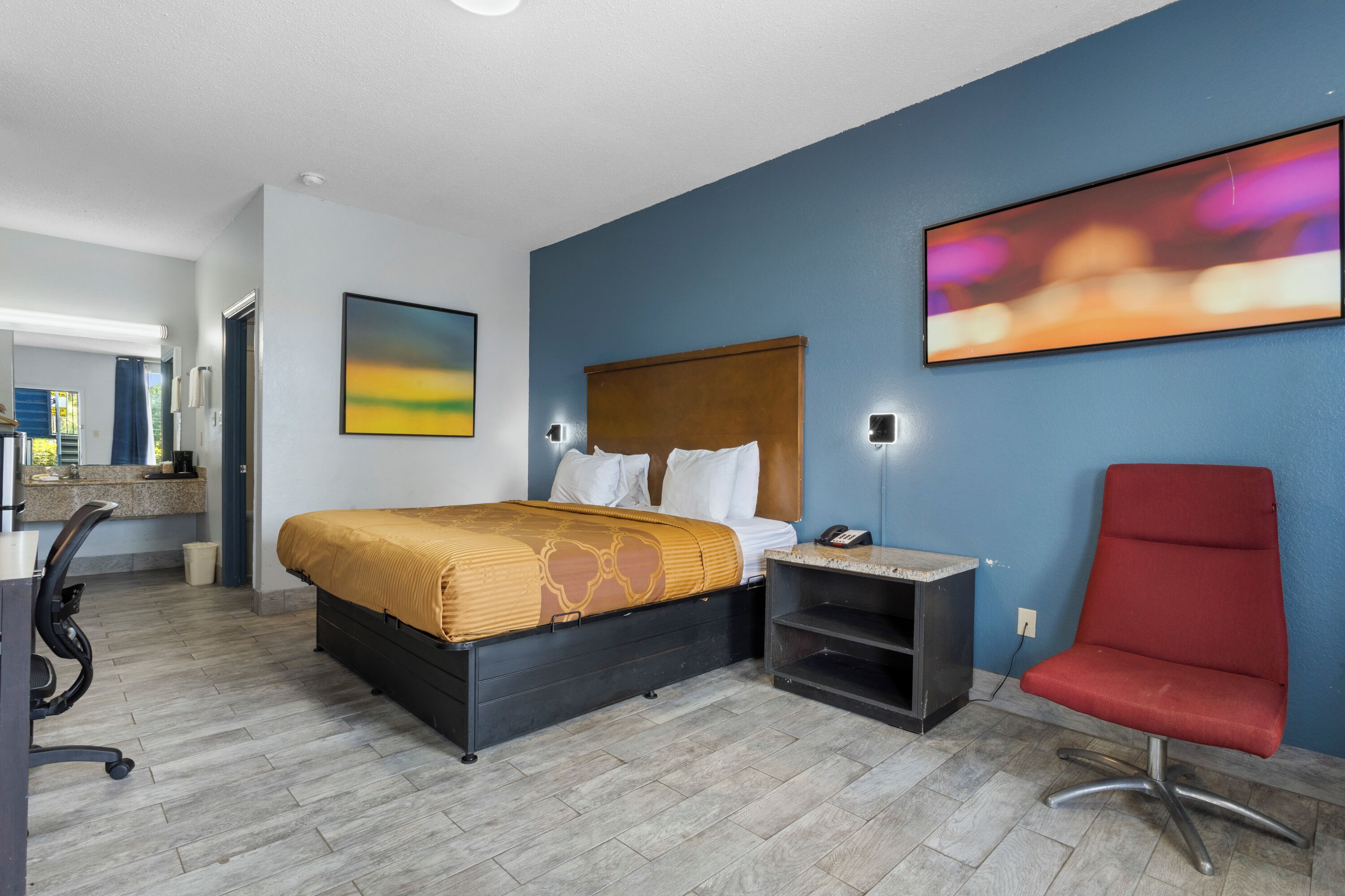 Ein Hotelzimmer mit Bett, Schreibtisch, Stuhl und einem Bild an der Wand.