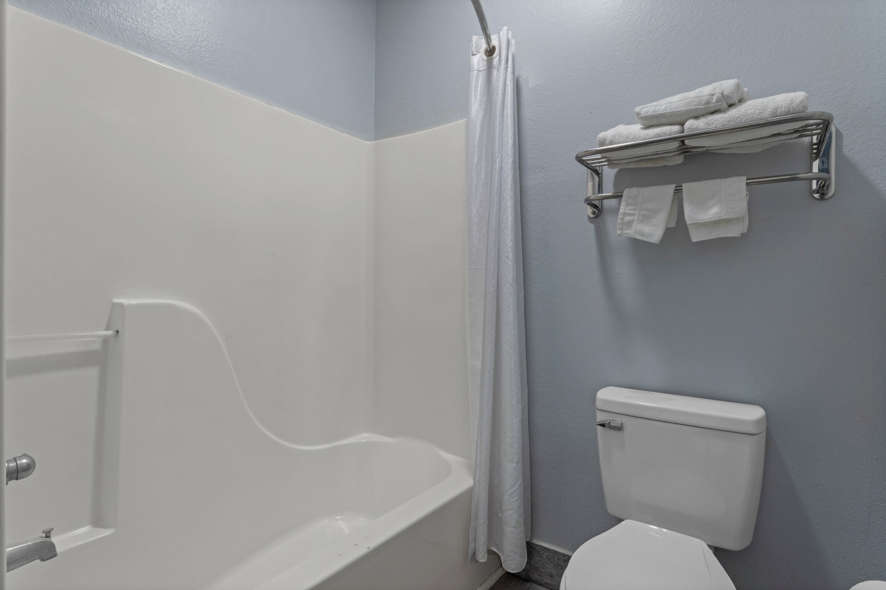 A bathroom with a bathtub, toilet, and towel rack.