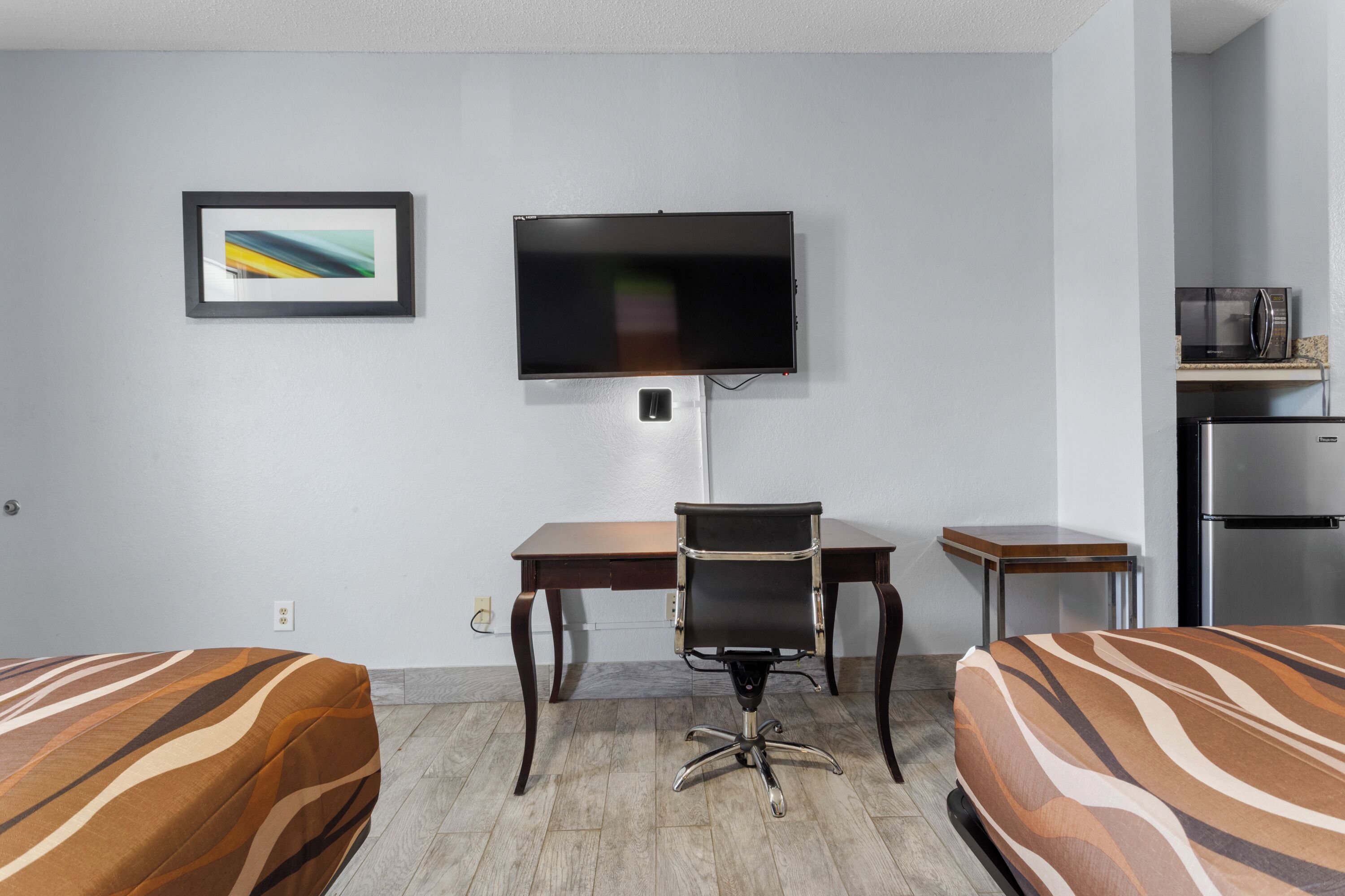 Hotelkamer met twee bedden, een bureau, een stoel, een televisie, een magnetron en een koelkast.