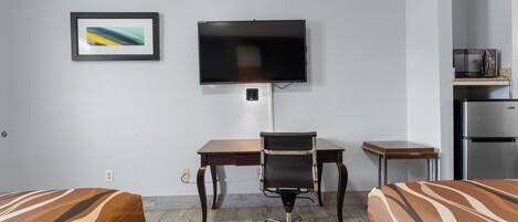 Hotelkamer met twee bedden, een bureau, een stoel, een televisie, een magnetron en een koelkast.