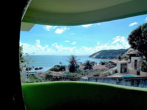 A coastal view with a clear sky, a beach, and a hill with buildings. - Bamboo Flat Residencial (Natal)