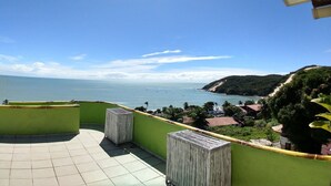 Eine Terrasse mit Blick auf das Meer und eine grüne Hügelkuppe.