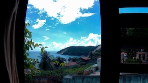 Blick aufs Meer vom Fenster aus, mit Grünflächen und Gebäuden.