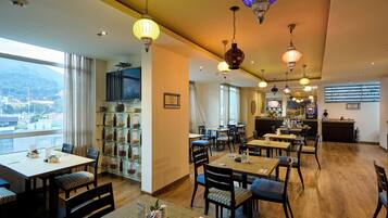 Un comedor de hotel con varias mesas y sillas, un bar y vistas a la ciudad.