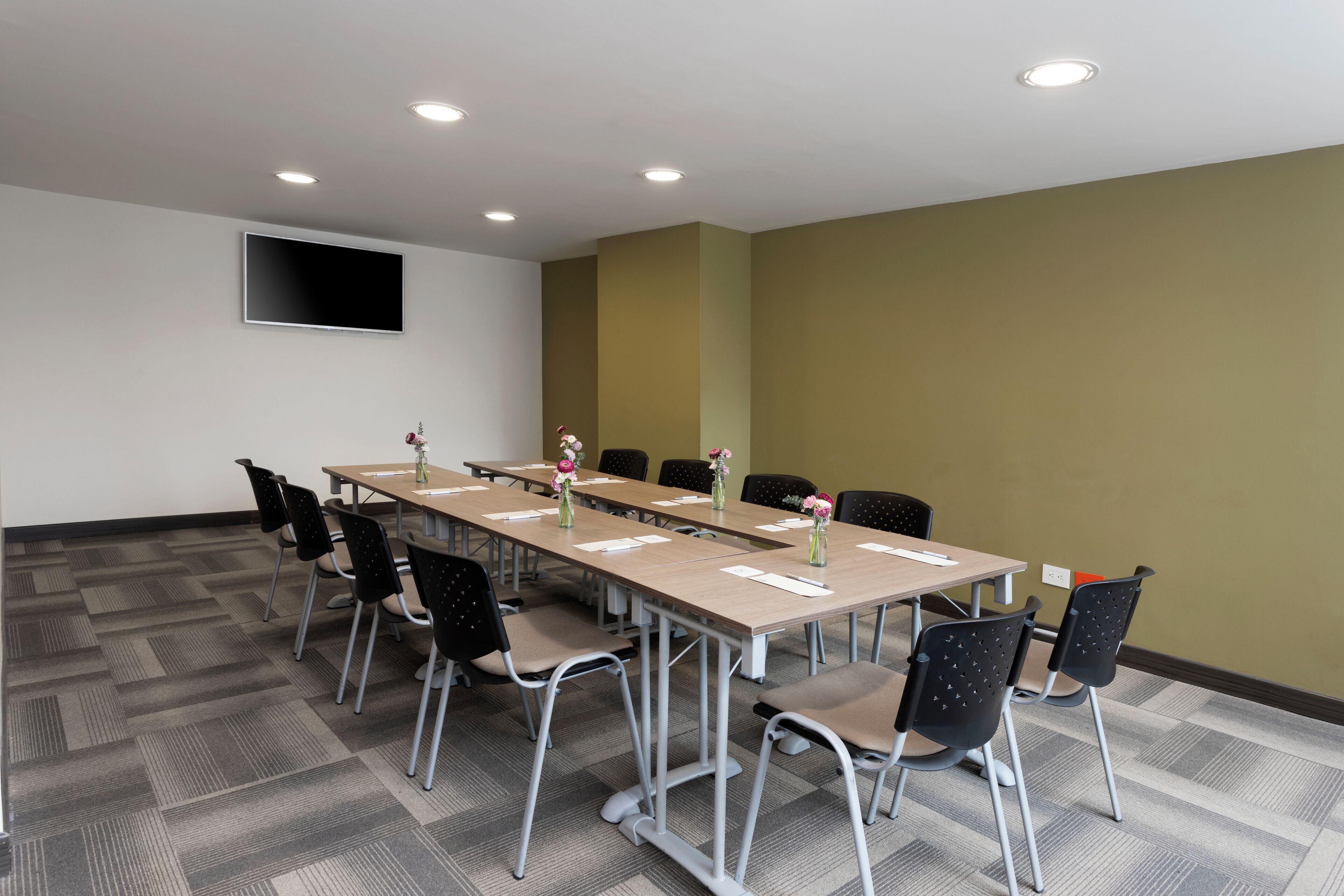 Ein Konferenzraum mit einem langen Tisch, Stühlen und einem Flachbildfernseher an der Wand.