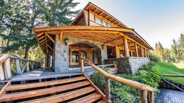 A wooden cabin with a stone foundation, wooden stairs, and a wooden deck. - Ruca Kuyen Golf & Resort (Villa La Angostura)