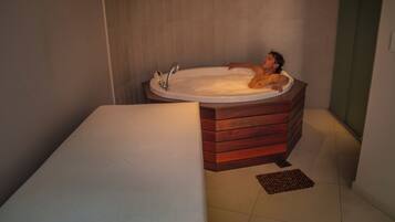 Un bagno moderno con una vasca da bagno in legno, un lavandino bianco e un piccolo tappeto sul pavimento.