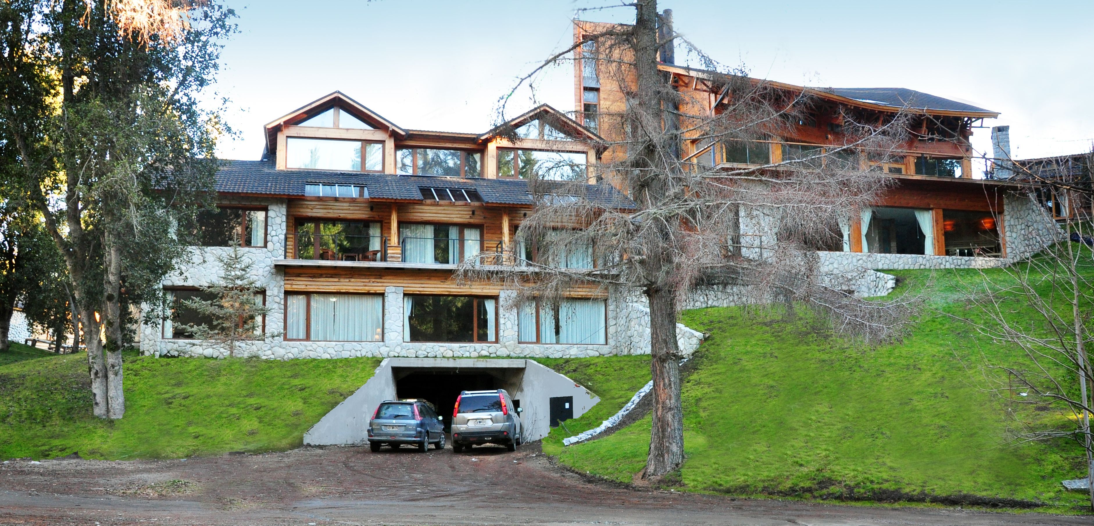 A large, multi-story house with a stone facade, a garage, and a driveway.