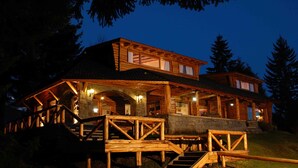 A log cabin with a porch, stairs, and a stone wall. - Ruca Kuyen Golf & Resort (Villa La Angostura)