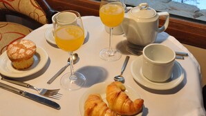 A table with breakfast items including croissants, orange juice, and a teapot, set against a snowy view. - Ruca Kuyen Golf & Resort (Villa La Angostura)