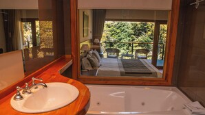 A bathroom with a wooden vanity, a white sink, and a large bathtub. - Ruca Kuyen Golf & Resort (Villa La Angostura)