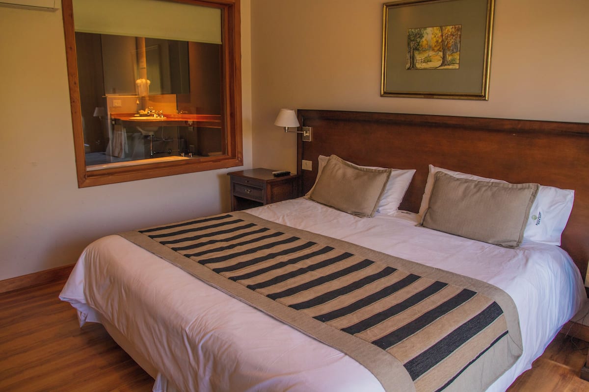 A neatly made bed with a striped bedspread, a wooden headboard, and a nightstand with a lamp.