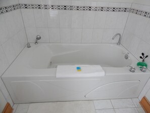 A white bathtub with a small towel and a bottle of shampoo.