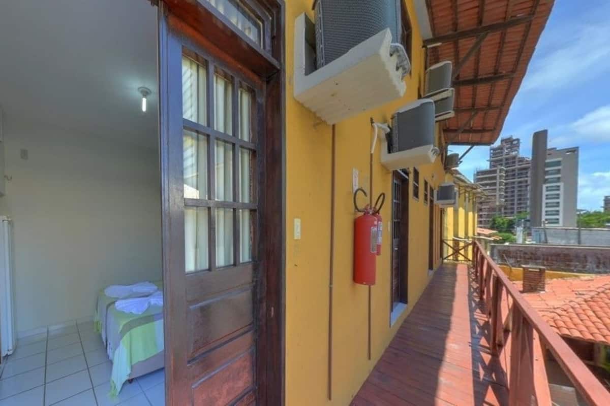Un pasillo de hotel con una puerta de madera, unidades de aire acondicionado y un extintor.
